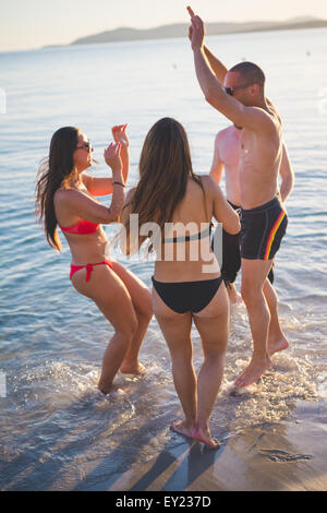 Groupe de jeunes amis multiethnique les femmes et les hommes à la plage en été, sauter et danser au coucher du soleil - insouciance, concepts d'amitié Banque D'Images