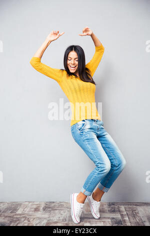 Portrait of a young woman dancing sur fond gris Banque D'Images