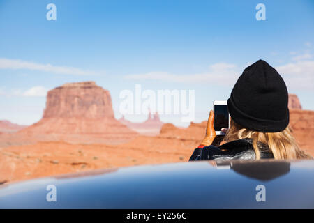 Vue arrière du Mid adult woman photographing Monument Valley sur smartphone, Utah, USA Banque D'Images