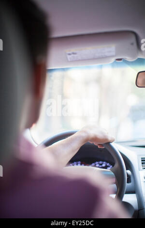 Au-dessus de l'épaule view of young businessman driving car Banque D'Images