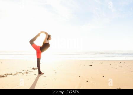 Woman in yoga pose sur plage Banque D'Images