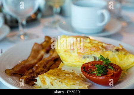 Une omelette de saumon fumé et fromage avec du bacon et pommes de terre rissolées tomates grillées Banque D'Images