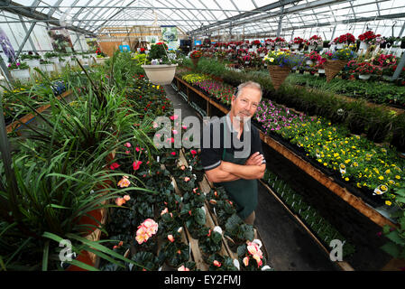 Un homme debout dans une serre avec des étagères de plantes. Banque D'Images