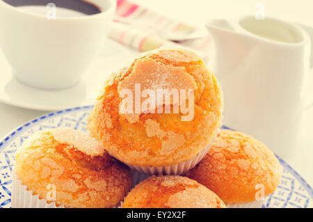 La plaque d'un gros plan avec quelques madeleines, la plaine espagnol typique, muffins, sur une table dressée avec une tasse de café et un pot à lait en t Banque D'Images