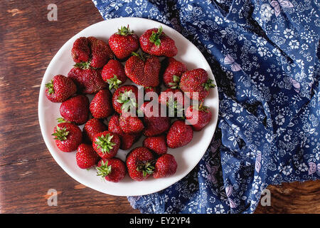 Plaque blanche avec jardin frais mûrs fraises sur table en bois. Style rustique foncé. Vue d'en haut Banque D'Images