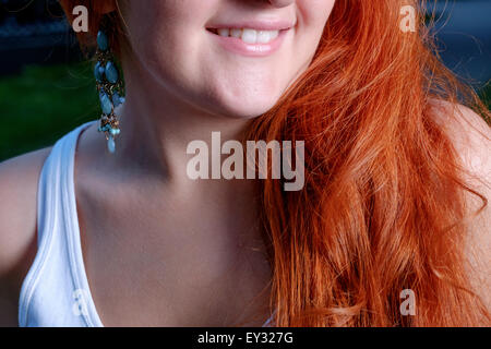La femme aux cheveux rouge sourit. Une partie du visage, lèvres gros plan Banque D'Images