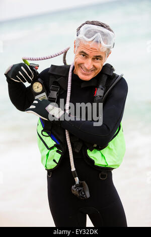 Portrait of a senior man mettre son matériel et de se préparer à faire de la plongée sous-marine, tout en se tenant sur une plage Banque D'Images