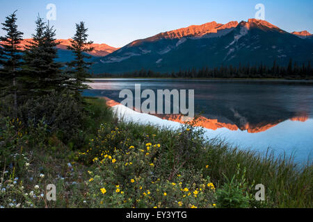 Montagnes reflétée dans un lac et le soleil qui se reflète sur les pentes couvertes de neige. Banque D'Images