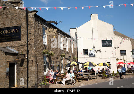 Les gens assis à l'extérieur des pubs dans le village de Hawes, Yorkshire Dales national park, England, UK Banque D'Images