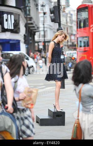 Piccadilly Circus, Londres, Royaume-Uni. 21 juillet 2015. Un modèle se trouve sur une case dans Piccadilly Circus lors d'un shoot de mode. © Matthieu Ch Banque D'Images