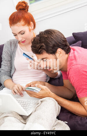 Couple sur le canapé dans le salon, avec des expressions du visage pensif, tandis qu'ami est couché sur les genoux d'h Banque D'Images