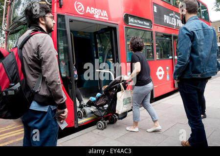 Mère avec enfant en poussette monter dans un bus de Londres à un arrêt d'autobus, Islington, Londres UK Banque D'Images