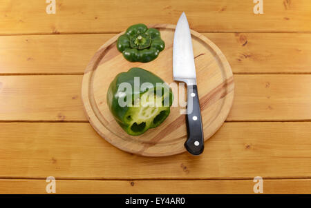 Poivron vert cru ouvrir en tranches avec un couteau de cuisine sur une planche à découper en bois, l'accent sur les graines et la membrane à l'intérieur Banque D'Images