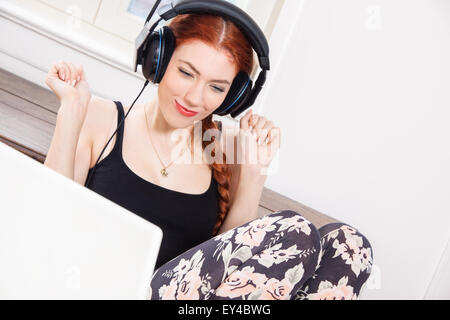 Happy Young Woman Laughing tout en écoutant la musique drôle utiliser de casque à l'intérieur de sa chambre. Banque D'Images