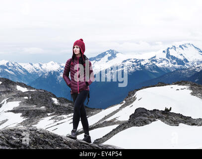 Jeune femme randonnées avec de la neige sur la montagne dans l'arrière-plan, le mont Whistler, Colombie-Britannique, Canada Banque D'Images