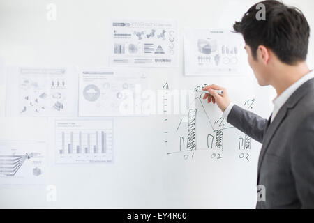 Young businessman writing on whiteboard in office Banque D'Images