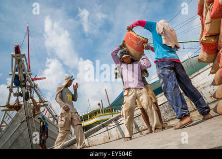 Travailleurs transportant des sacs de ciment d'un camion à un navire phinisi au port traditionnel de Sunda Kelapa à Penjaringan, dans le nord de Jakarta, Jakarta, Indonésie. Banque D'Images