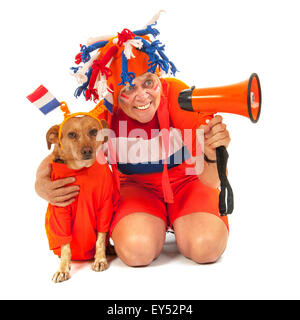 Supporter de football néerlandais et son chien à l'orange avec des drapeaux de couleur orange Banque D'Images