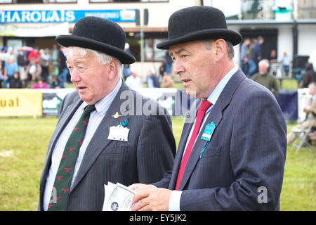 Builth Wells, Powys, Wales, UK. 22 juillet 2015. Royal Welsh Show les juges avec leur chapeau melon dans le bétail leur oeil coulé plus de bétail dans une douche à effet pluie. Les quatre jours de l'événement a attiré plus de 240 000 visiteurs et 7 000 entrées à l'élevage le plus grand salon de l'agriculture. Banque D'Images