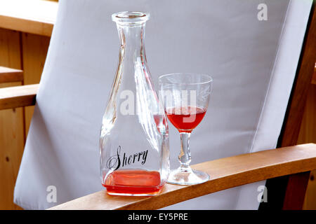 Bouteille de sherry intéressantes avec le verre sur l'accoudoir chaise Banque D'Images