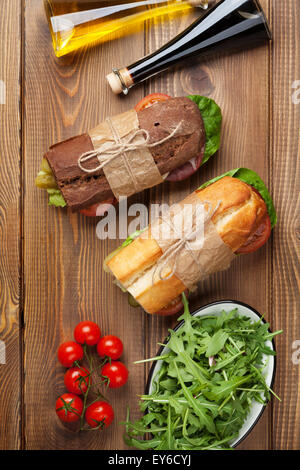 Deux sandwichs avec de la salade, jambon, fromage et tomates, salade et épices sur table en bois. Vue d'en haut Banque D'Images