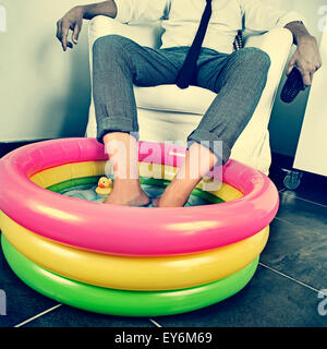 Un jeune homme en fonction de ses pieds tremper dans l'eau d'une piscine gonflable à l'intérieur, avec un effet dramatique, illustrant le concept de stayi Banque D'Images