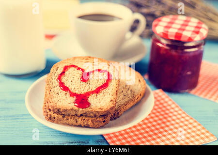 Jam formant un coeur sur un pain grillé, sur une table rustique en bois bleu, avec un effet inter-processus Banque D'Images