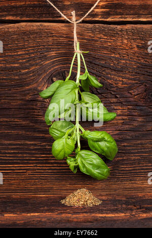 Le basilic frais suspendu à chaîne et basilic sec spice old vintage sur fond de bois. Herbes culinaires. Banque D'Images