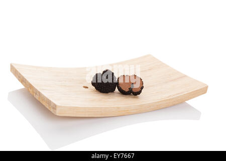 Truffes, champignons rares. Couper les truffes sur plaque de bois isolé sur fond blanc. Ingrédients de cuisine culinaire de luxe. Banque D'Images