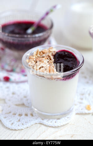 Petit pot avec du yaourt fait maison avec de la confiture de cassis et granola (graines de tournesol, maïs, flocons d'avoine et d'orge et les écrous) Banque D'Images