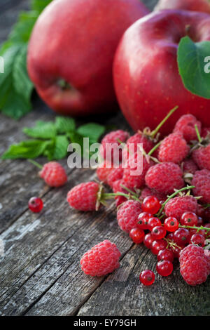 Groseille, framboise et pommes rouges sur la vieille table en bois, mélange de couleur rouge concept vitamines Banque D'Images