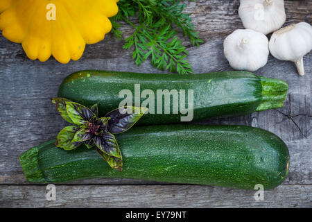 Zuchinni vert frais, squash avec des feuilles de basilic et l'ail sur planche de bois, vue du dessus Banque D'Images