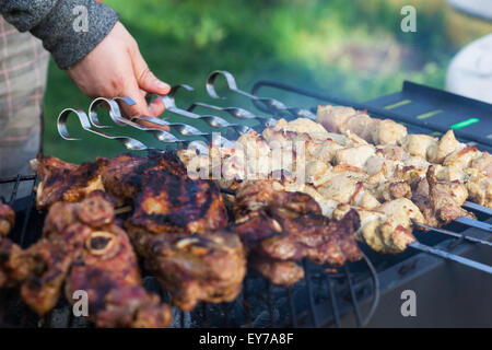 La cuisson des steaks d'agneau et de porc sur le gril, kebab brochette de viande de porc à la main, à l'extérieur. Focus sélectif et peu profondes 6 Banque D'Images