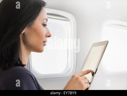 Young woman using tablet sur avion Banque D'Images