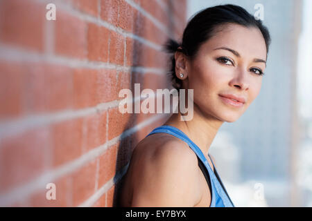 Portrait de jeune femme par brick wall Banque D'Images