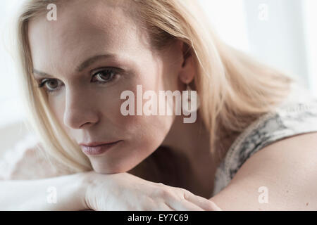 Pensive young woman lying on bed Banque D'Images