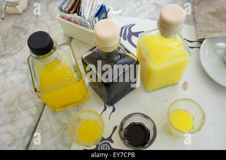 Trois bouteilles et trois verres de liqueurs sur une table. Banque D'Images