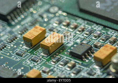 Macro-photo de la carte de circuit imprimé (PCB) montrant les condensateurs à oxyde de tantale jaune (une terre rare). Macro de gros plan de circuit, détail d'une carte de circuit imprimé. Banque D'Images