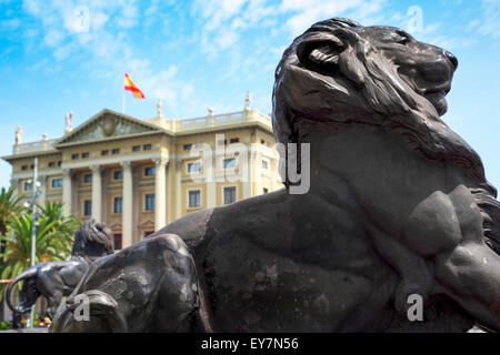 Détail d'un lion de bronze à la base du monument de Christophe Colomb à Barcelone, Espagne, avec la Comandancia bâtiment dans le backgroun Banque D'Images