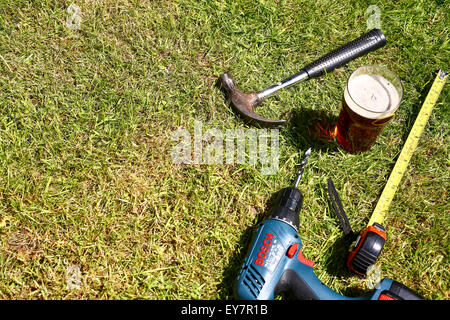 Outils de travail posés sur l'herbe avec une pinte de bitter à l'été Banque D'Images