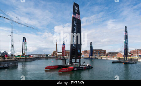 Portsmouth, Royaume-Uni. 23 juillet 2015. Quatre des catamarans AC45f s'asseoir dans un bassin à Portsmouth Historic Dockyard. L'équipe Oracle USA, BAR, couverture de l'équipe d'Artemis en Suède et Emirates Team New Zealand avait déjà été tendit à travers de leur poste de nuit et l'équipe de France Grouparama est assis sur la région d'être attaché à la grue. Credit : MeonStock/Alamy Live News Banque D'Images