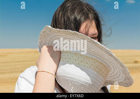 Fille avec chapeau blanc dans la main dans le champ de blé Banque D'Images