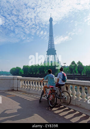 Couple sitting on bikes en regardant vers la Tour Eiffel à Paris Banque D'Images