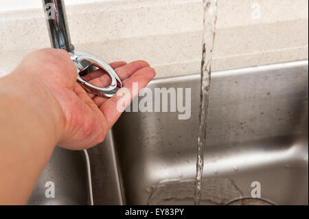 Tourner à la main sur le robinet d'eau au-dessus de l'évier Banque D'Images