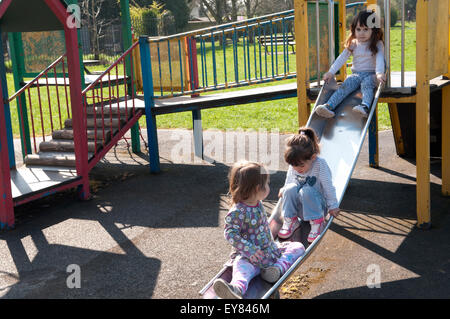 Trois petites filles jouant ensemble sur une diapositive Banque D'Images