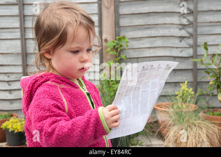 Gros plan d'une petite fille se concentrer, regarder une notice Banque D'Images