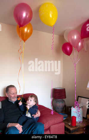 Baby Girl sitting on her lap grands-pères jouant avec un ballon Banque D'Images