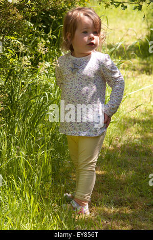 Petite fille debout dans l'herbe haute Banque D'Images