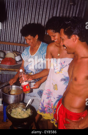 Frère, sœur et mère la cuisson et la préparation des aliments dans la cuisine typique à la maison sur l'île de La Digue aux Seychelles Banque D'Images