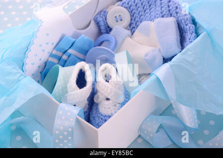 Un garçon de son thème bleu boîte de cadeau de douche de bébé avec des vêtements de bébé, bavoir, bonnet, chaussures, chaussettes et sucette. Banque D'Images